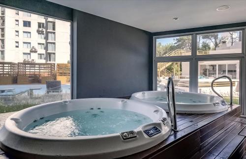 two tubs in a bathroom with a large window at Wind Tower, Punta del Este in Punta del Este