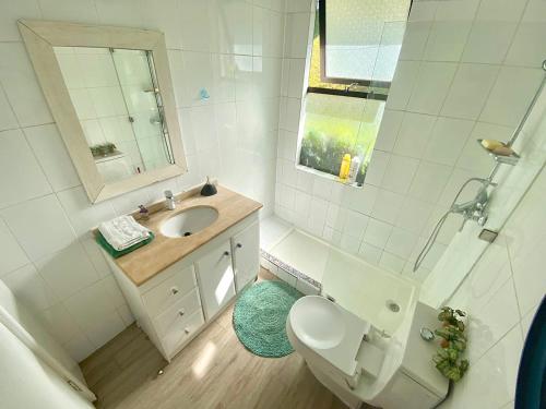 uma casa de banho com um WC, um lavatório e um espelho. em Hermoso bungalow con vista al mar em Concón