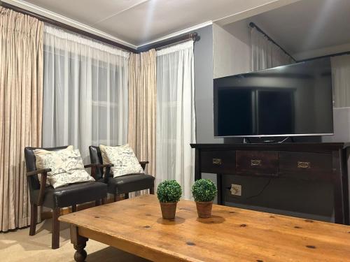 sala de estar con TV, mesa y sillas en 741 Tetra Self Catering Accommodation en Pretoria