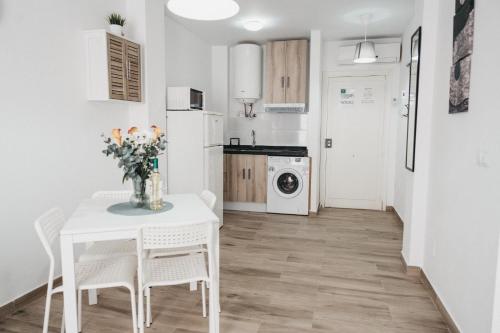 a kitchen with a white table and chairs and a white refrigerator at Marimel Nerja Alojamientos in Nerja