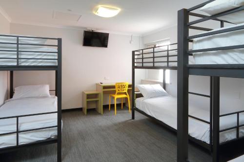 a room with two bunk beds and a desk at Palm Beach Hotel in Gold Coast