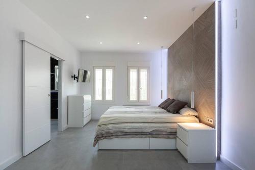 ein weißes Schlafzimmer mit einem Bett und einem großen Spiegel in der Unterkunft Espectacular villa close to Sevilla - Sevillarooms in Valencina de la Concepción