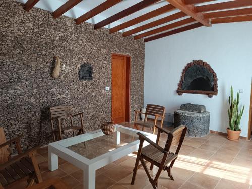 sala de estar con mesa, sillas y pared de piedra en Casa de Familia Felipe y Martin, en Tías
