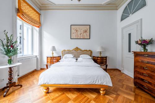 a white bedroom with a large bed and wooden floors at Malostranská Residence in Prague