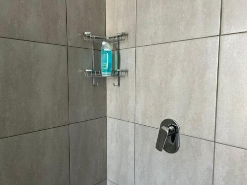 a shower with a blue soap bottle on a wall at Lilly's Gold in Johannesburg