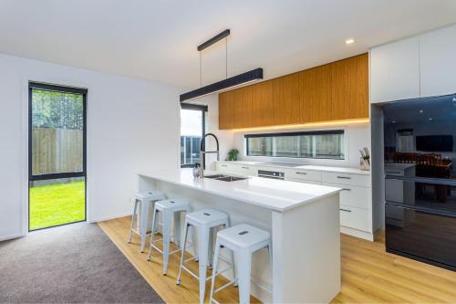 a kitchen with a large white island with bar stools at Elegant, Executive Retreat in Methven