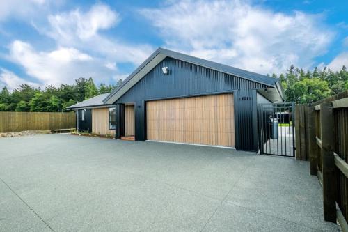 a house with two garage doors and a fence at Elegant, Executive Retreat in Methven