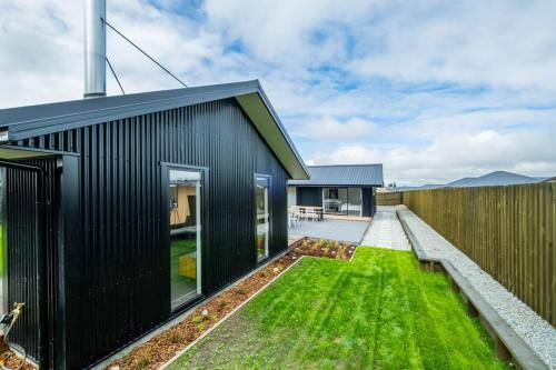 a black house with a green yard at Elegant, Executive Retreat in Methven