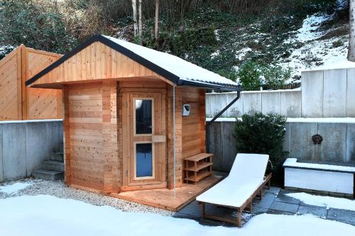 una casa exterior de madera con banco y techo cubierto de nieve en Vallhouse - Massage, Sauna, Darts, Switch & mehr, en Vallendar