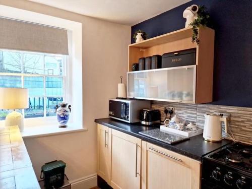 a kitchen with a black counter top with a microwave at The kings in Denbigh