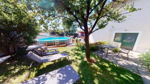 a yard with benches and a tree and a swimming pool at Weingut Bohrn Himmelbett in Herrnbaumgarten