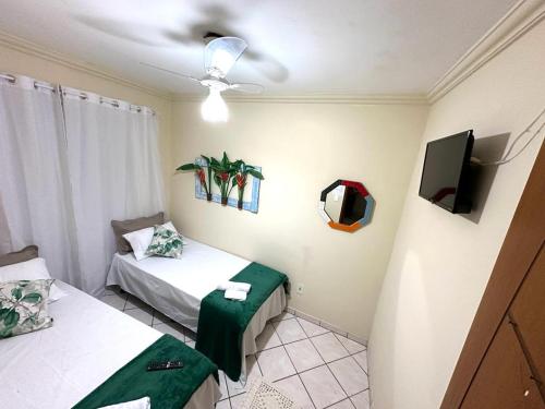 a room with two beds and a flat screen tv at Quarto Ponta Negra in Angra dos Reis