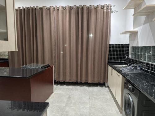 a kitchen with a washer and dryer in front of a curtain at Waterfalls Manor in Lusaka