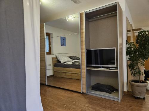 a mirror reflecting a bedroom with a bed and a television at Einfaches ruhiges Apartment in Laichingen