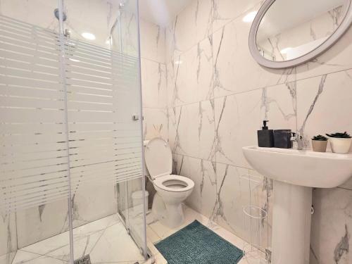 een badkamer met een toilet, een wastafel en een spiegel bij 1BD Beach Apartment in Paphos City