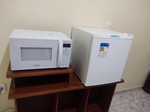 a microwave and a refrigerator on a wooden stand at QUARTO CONFORTAVEL COM GARAGEM in Holambra