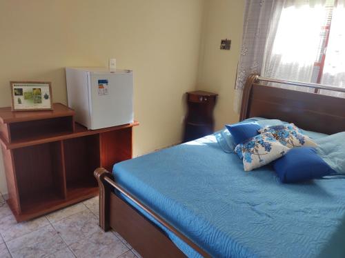 um quarto com uma cama com lençóis azuis e uma janela em QUARTO CONFORTAVEL COM GARAGEM em Holambra