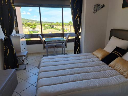 um quarto com uma cama, uma mesa e uma janela em Naturistecapdagde APHRODITE em Cap d'Agde