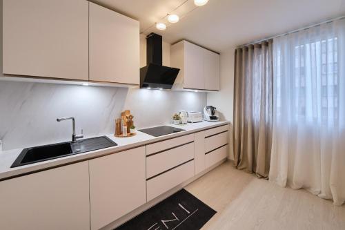 cocina con armarios blancos, fregadero y ventana en Appartement parisien au cœur de Montparnasse, en París