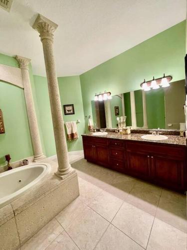 a bathroom with two sinks and a bath tub and a large mirror at King Suite & Jacuzzi Luxe Getaway in Port St Lucie in Port Saint Lucie