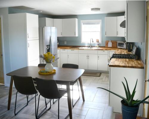 タオスにあるFully Furnished, Serene Taos Houseの白いキャビネット、テーブルと椅子付きのキッチンが備わります。