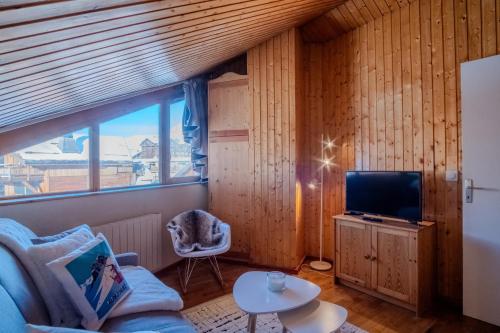 a living room with a couch and a tv at Cosy duplex with view in Huez - Welkeys in LʼHuez