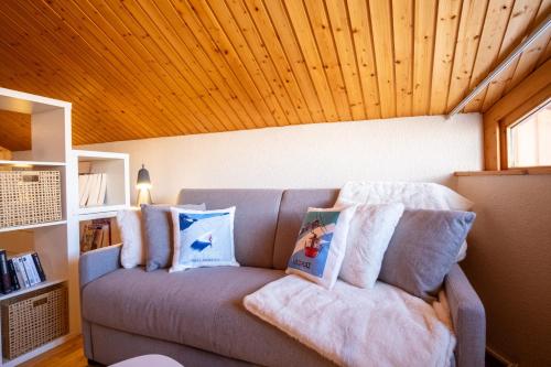 a couch in a room with a wooden ceiling at Cosy duplex with view in Huez - Welkeys in LʼHuez