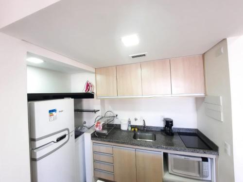 a kitchen with a white refrigerator and a sink at Flat Apart-hotel QI Ibirapuera Perto do Shoping in Sao Paulo