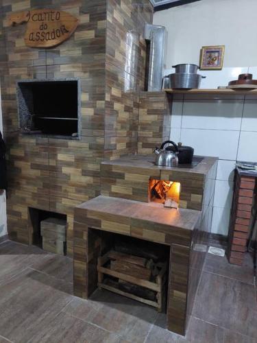 a living room with a fireplace and a tv at Casa com 2 quartos, garagem, a 3 quadras da praia! in Passo de Torres