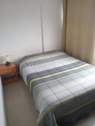 um pequeno quarto com uma cama e uma mesa de cabeceira em Habitacioneswilson em Iquique