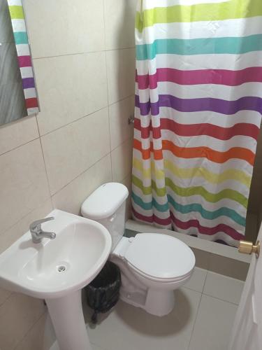 uma casa de banho com um lavatório, um WC e uma cortina de chuveiro. em Habitacioneswilson em Iquique