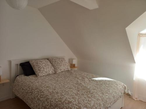 - une chambre avec un lit et un mur blanc dans l'établissement Maison chaleureuse idéalement située, 