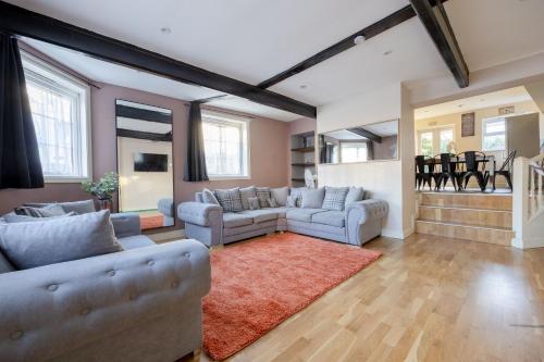 a living room with two couches and a red rug at BIG House close to Metro Underground - Sleeps up to 13 in London