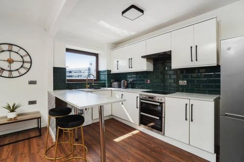 una cucina con armadi bianchi e un orologio sul muro di New Slick Finnieston Pad w/ Free Parking a Glasgow