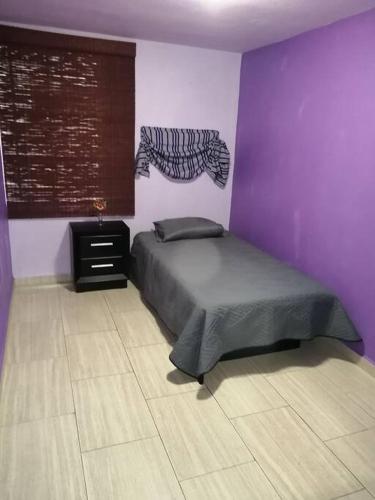 - une chambre avec un lit et un mur violet dans l'établissement Departamento privado en condominio, à Mexico