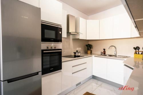 a kitchen with white cabinets and black appliances at Sea Views in a Stunning 2BR Apartment in St Paul's Bay in St. Paul's Bay