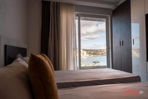 a bedroom with a bed with a view of the ocean at Seaside Magic From a Stunning Apartment in St. Paul's Bay