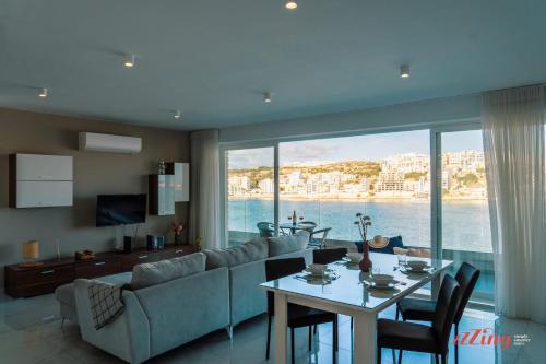 a living room with a couch and a table with chairs at Sea Views in a Stunning 2BR Apartment in St Paul's Bay in St. Paul's Bay