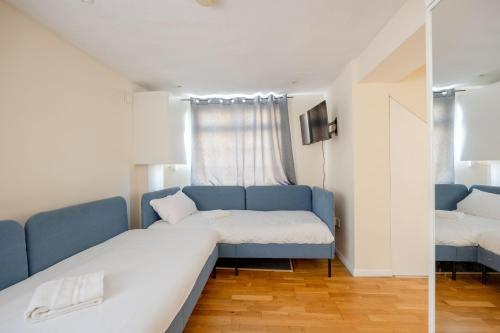 1 dormitorio con sofá azul y ventana en Heads Down & Coffee Mornings, en Londres