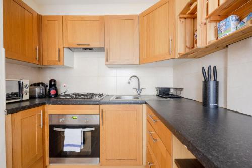 a kitchen with wooden cabinets and a stove top oven at Heads Down & Coffee Mornings in London