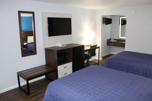 Habitación de hotel con 2 camas, escritorio y TV. en Knights Inn St. George, en Saint George