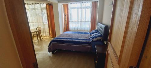 a small bed in a room with two windows at Sofia in Oruro