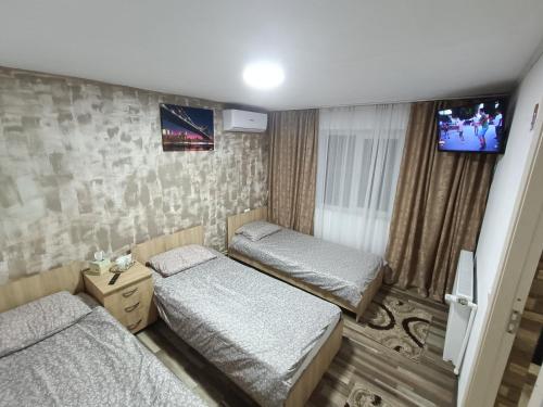 2 Betten in einem Zimmer mit einem TV an der Wand in der Unterkunft Casa Bianca Pensiune in Târgu Jiu