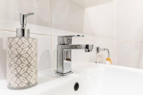 a bathroom sink with a soap dispenser next to a faucet at Stylish City Pad with Free Private Parking in Glasgow