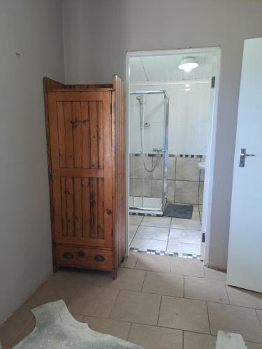 a bathroom with a shower and a wooden door at Lynthorn Farm Cottage in Frere