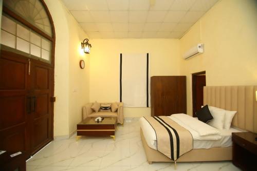 a bedroom with a bed and a chair and a table at Peshawar Barracks Hotel Estb-1867 in Peshawar