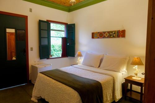 a bedroom with a bed and two lamps and a window at Pousada Canto Verde in Tiradentes