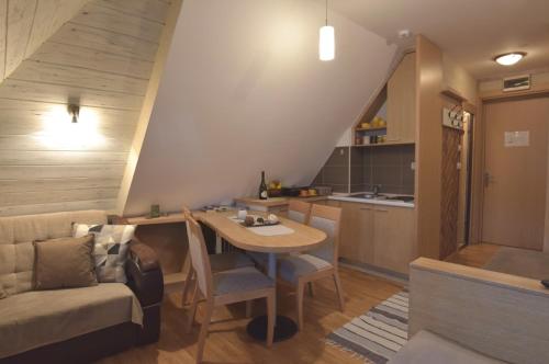 a kitchen and a living room with a table and a couch at Konaci Kopaonik Lux Apartmani in Kopaonik