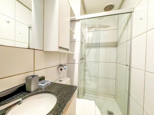 a bathroom with a sink and a glass shower at Park Studios Vaga Garagem in Brasilia
