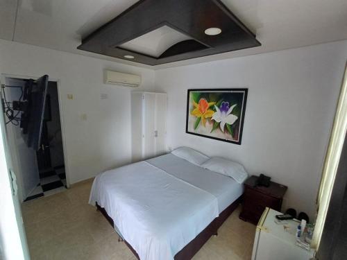 a bedroom with a bed and a painting on the wall at HOTEL DULCES SUEÑOS in Buenaventura